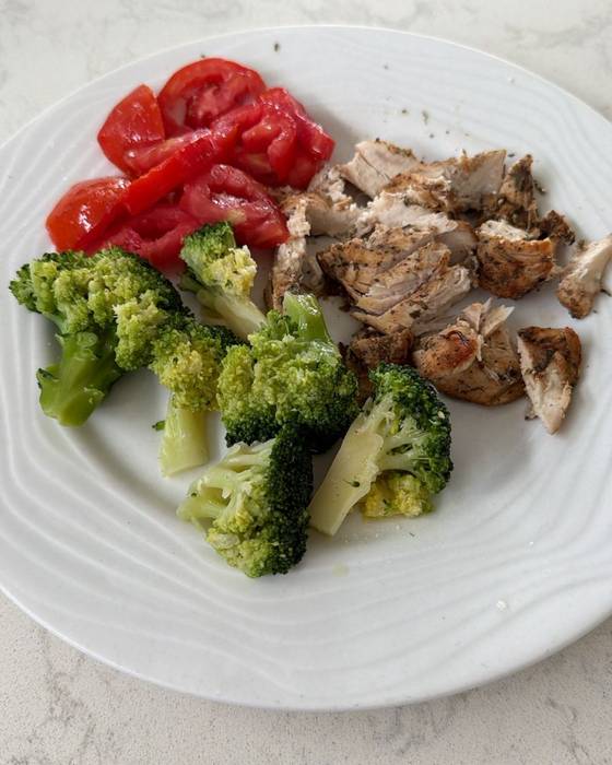 Sliced chicken breast with broccoli and fresh tomatoes.