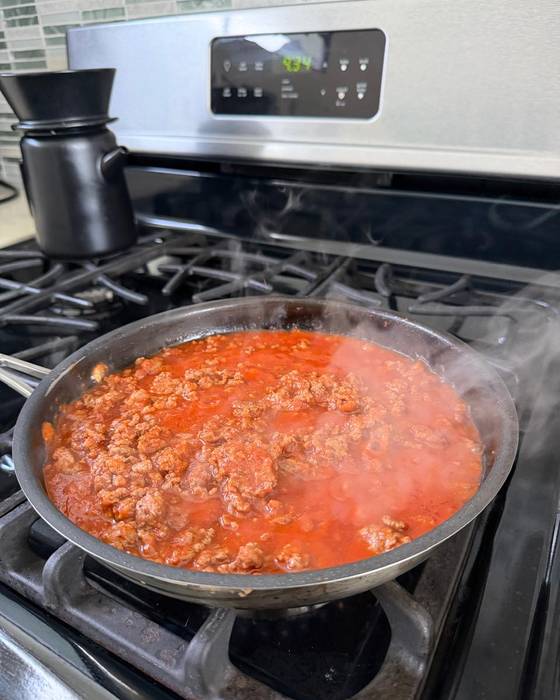 Mince simmering in tomato sauce in a pan.
