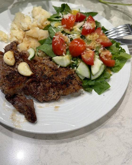 Steak with a tomato, cucumber and leaf salad.